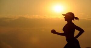 Mujer corriendo al amanecer, representando salud y bienestar.