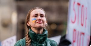 Mujer ucraniana con bandera en el rostro y letrero "Stop Putin".