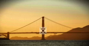 Puente al atardecer con el icono de Puntos de Encuentro en el centro, representando la conexión intercultural.